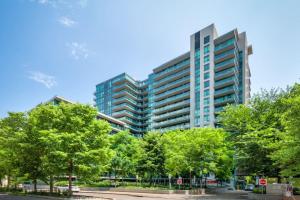 a tall building with trees in front of it at Chic 1BR plus Den Condo with Fast WiFi and Free Parking in Toronto