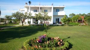 a white house with a green yard with flowers at Luce di Sole Apartment in Sveti Nikola