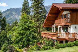 a log home with a deck and mountains in the background at Fox Den Bed & Breakfast in Leavenworth