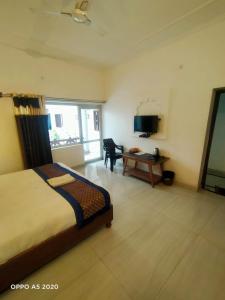 a bedroom with a bed and a desk and a television at Chelsea Palace Khajuraho in Khajurāho
