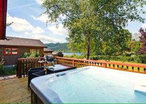 una bañera de hidromasaje en una terraza junto a una casa en Lodge by the Lake - Lake District - Hot Tub, en Bassenthwaite