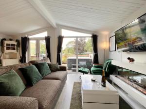 Una sala de estar con un sofá y una ventana grande. en Lodge by the Lake - Lake District - Hot Tub, en Bassenthwaite
