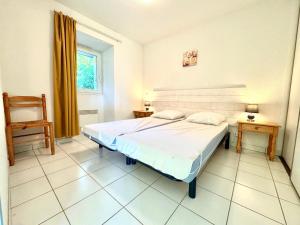 a bedroom with a bed and a chair and a window at La Vallée Appartement 31 - Thermes Neyras les Bains in Meyras