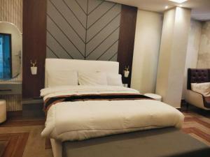 ein Schlafzimmer mit einem großen weißen Bett und einem Stuhl in der Unterkunft Hotel 44 in Murree