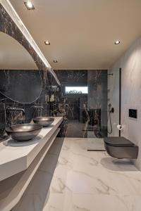 a bathroom with three sinks in a room with marble walls at Costas Luxury Villas - Costa's Villa in Koskinou