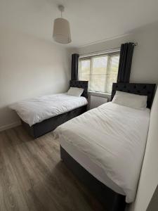 zwei Einzelbetten in einem Zimmer mit Fenster in der Unterkunft 3 Bed Home From Home Contractor & Family Stay DY5 in Woodside