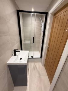 ein Badezimmer mit einem weißen Waschbecken und einer Dusche in der Unterkunft 3 Bed Home From Home Contractor & Family Stay DY5 in Woodside