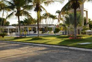 a resort with palm trees in front of a building at Hotel Pousada Lord in Teixeira de Freitas