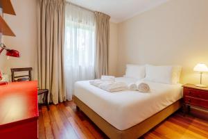 a bedroom with a large white bed with towels on it at Villa Luzia by Portugal Active in Viana do Castelo