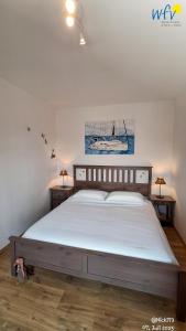 ein Schlafzimmer mit einem großen Bett mit einem Gemälde an der Wand in der Unterkunft Haus Möwennest Ferienwohnung Kiek op de Toorns in Borkum