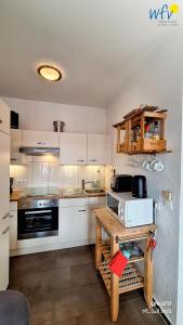 eine Küche mit weißen Schränken und einem Holztisch in der Unterkunft Haus Möwennest Ferienwohnung Kiek op de Toorns in Borkum