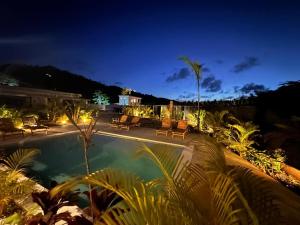 a swimming pool at night with chairs and lights at Kaia Beach Lodge en Cosón in Las Terrenas
