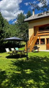 einem Picknicktisch mit Stühlen und einem Regenschirm vor einem Haus in der Unterkunft Hébergement 4 étoiles Accès Pied des Pistes en Navette Gratuite in Saint-Chaffrey