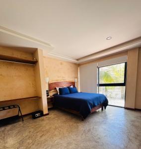Un dormitorio con una cama azul y una gran ventana. en Kauil Tulum, en Tulum
