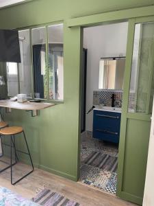 Una habitación con una puerta verde, una mesa y un escritorio. en La Maison du Bonheur, en Thaims