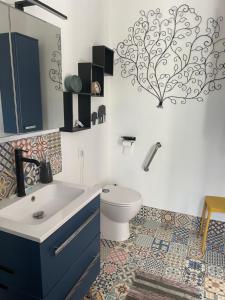 Un baño con un lavabo azul y un inodoro. en La Maison du Bonheur, en Thaims