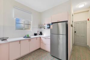 Chic & Cozy Stay in Trendy Miramar في سان خوان: مطبخ مع خزائن بيضاء وثلاجة