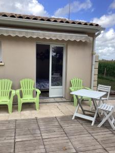 2 sillas verdes y una mesa en el patio en La Maison du Bonheur, en Thaims