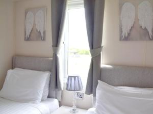 a bedroom with two beds and a window with angel wings at Elm 34 Hot Tub in Garton