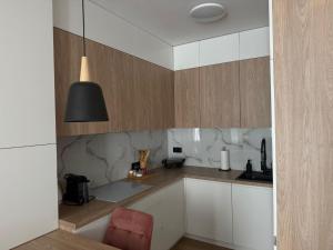 a kitchen with white cabinets and a black lamp at Apartament Pod Areną in Krakow