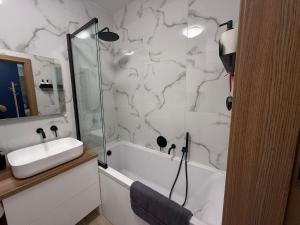 Un baño blanco con lavabo y ducha. en Apartament Pod Areną, en Cracovia 20 fotos más