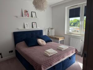 Un dormitorio con una cama azul con toallas. en Apartament Pod Areną, en Cracovia