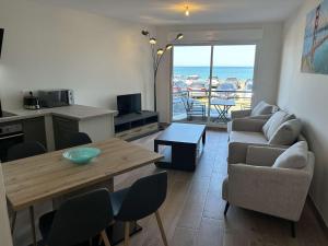 sala de estar con mesa, sofá y cocina en 530 - Appartement T3, à Erquy, avec pleine vue mer, en Erquy