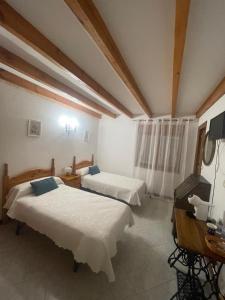 a bedroom with two beds and a television in it at Hostal Cholo in Brañosera