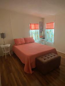 een slaapkamer met een bed, een poef en 2 ramen bij Misty falls in Ormond Beach