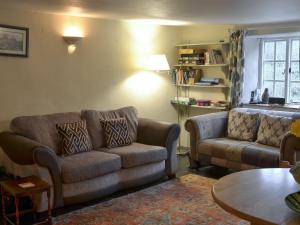 ein Wohnzimmer mit einer Couch, einem Sessel und einem Tisch in der Unterkunft Blackberry Cottage in Kenton