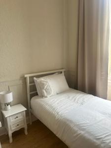 a bedroom with a white bed and a nightstand with a lamp at Modern Twin Room In The Heart Of Edinburgh in Edinburgh