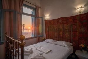 a bed in a bedroom with a window and a bedspread at Pension Nora in Chania