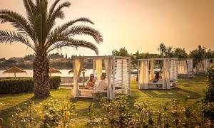 a group of people sitting in chairs in domed tents next to a palm tree at Aminess Vival Maestral Hotel in Novigrad Istria