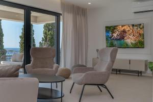 un salon avec deux chaises et une télévision dans l'établissement Villa Mariva, à Mlini