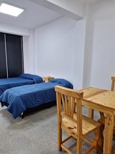 una stanza con due letti, un tavolo di legno e una panca di Santa Rita Dpto 9 a San Fernando del Valle de Catamarca