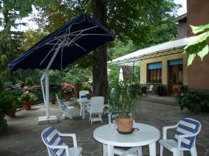 patio con tavolo, sedie e ombrellone di Hotel Villa Patrizia a Cutigliano