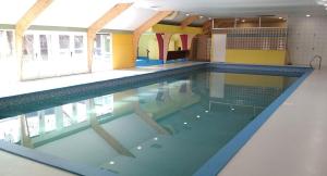 a swimming pool in a building with a large pool at Villa Pimpelmees - Sunclass 54 in Durbuy