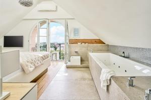 ein weißes Badezimmer mit einer großen Badewanne und einem Bett in der Unterkunft Boutique Suites and Residences Heidelberg- Alte Zigarrenmanufaktur in Heidelberg