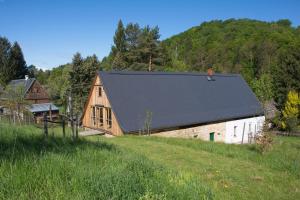 a barn with a black roof in a field at Chalupa Chřibská in Nieder Kreibitz