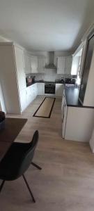 una cocina con armarios blancos y una silla negra. en SeaBreeze Portstewart, en Portstewart