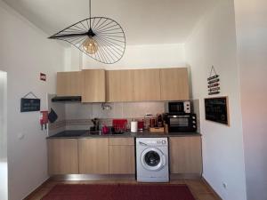 a kitchen with a washing machine and a microwave at Casa D' Oliveira in Castro Verde