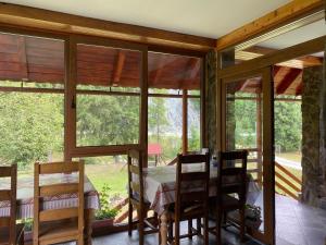 a dining room with windows and a table and chairs at PENSIUNEA SIMONA ARIESENI in Arieşeni