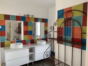 a bathroom with two sinks and a colorful tile wall at Villa vue mer plage à pied in Clohars-Carnoët
