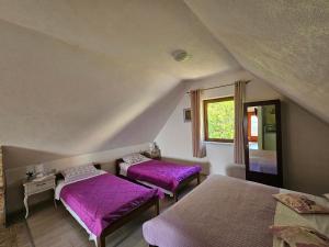 two beds in a room with purple sheets at Guesthouse Loncar in Plitvička Jezera