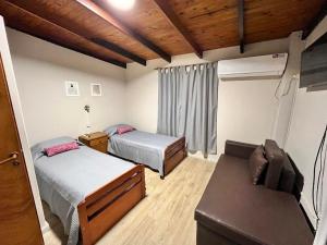 a small bedroom with two beds and a couch at Duplex Tucumán in Colón