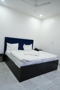 ファリーダーバードにあるMayur Hotel Near IMT College, Faridabadの黒枠のベッド、白いシーツ、枕