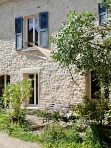 ein Steingebäude mit einem Fenster und Stühlen davor in der Unterkunft Ferme des Millonets - grand gîte in Vienne-en-Arthies