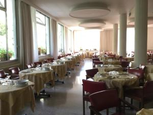 un comedor con mesas y sillas con mantelería blanca en Hotel Terme Vulcania, en Montegrotto Terme