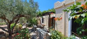 a house with a tree and a stone fence at Porto Heli Apartments in Palekastron