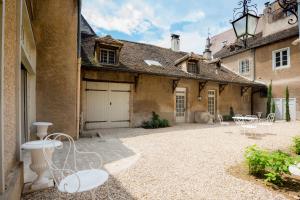 een binnenplaats van een oud gebouw met stoelen en tafels bij Les vignes blanches in Beaune